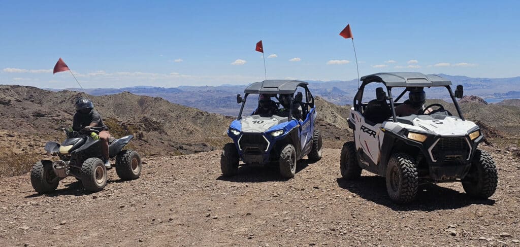 Adventurers enjoy an ATV tour near Las Vegas, Nevada, riding ATVs and UTVs on rocky desert trails with mountain views.