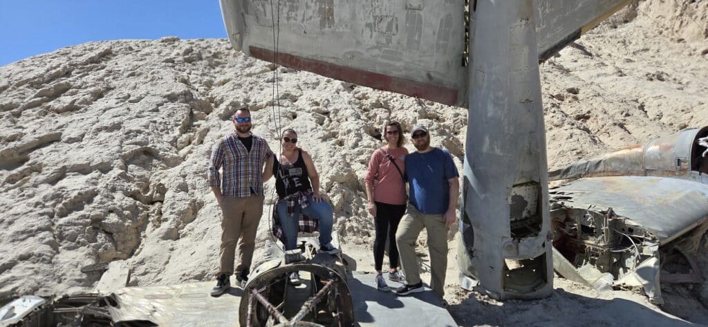 Four friends pose by an old airplane wreck in Nevada’s rocky desert near Las Vegas, during an ATV and Ghost Town sightseeing tour.