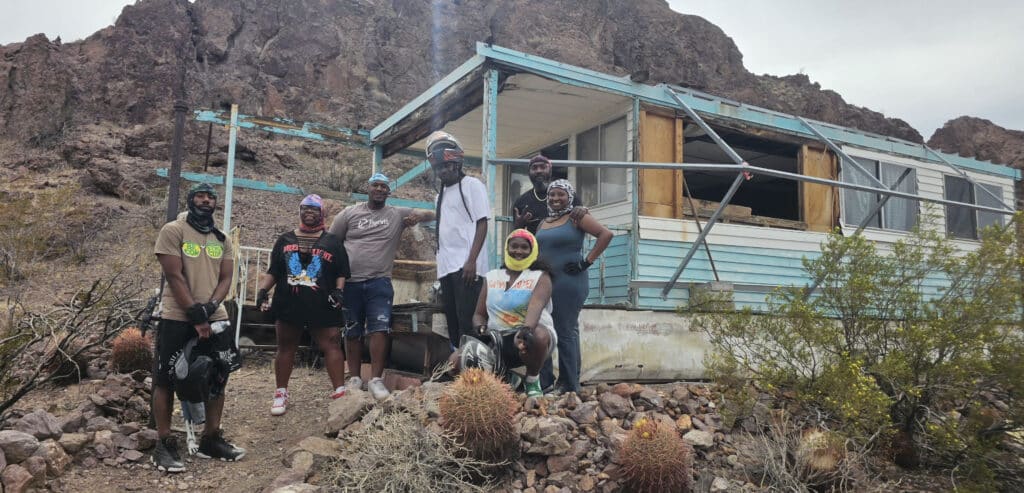 Seven friends pose by an abandoned trailer near Las Vegas, Nevada, after a thrilling RZR off-road ride in the desert.