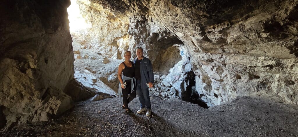 Smiling duo in a rocky Nevada cave near the Colorado River, sunlight streaming in—perfect after a Las Vegas ATV or RZR tour!.