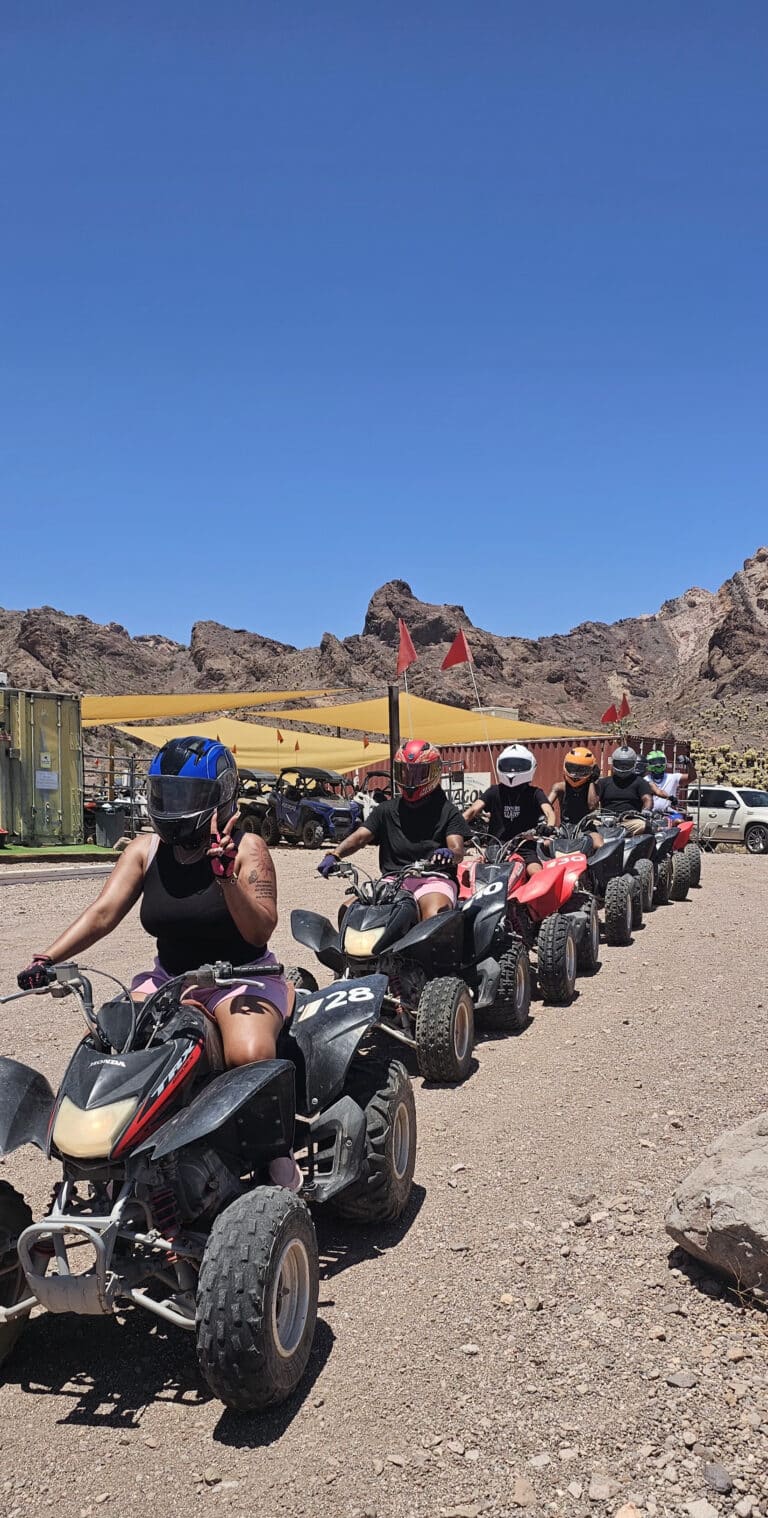 Adventure seekers in helmets gear up for ATV tours near Las Vegas, Nevada, with scenic mountains and the Colorado River behind them.
