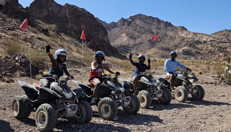 Adventure seekers enjoy an ATV tour near Las Vegas, Nevada, riding RZRs on rocky terrain with clear skies and mountain views.