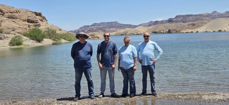 Four friends on a rocky Nevada shore by the Colorado River, near Las Vegas, after an exciting ATV and RZR off-road adventure.
