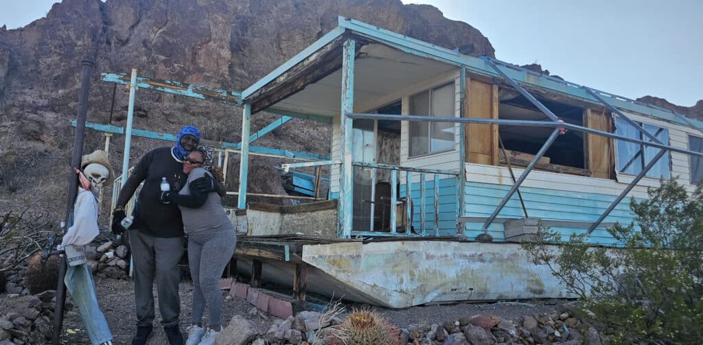 Couple embraces by ghostly, blue-white abandoned house near Nevadas Colorado River—perfect for Ghost Town tours & RZR adventures!.