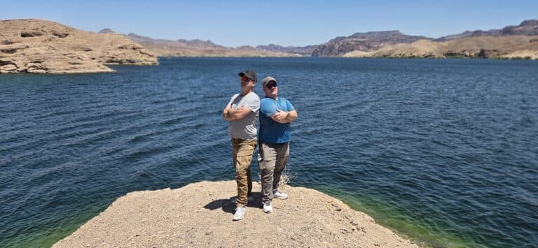 Two men pose back-to-back by the Colorado River near Las Vegas, Nevada—perfect for ATV tours and RZR off-road adventures.