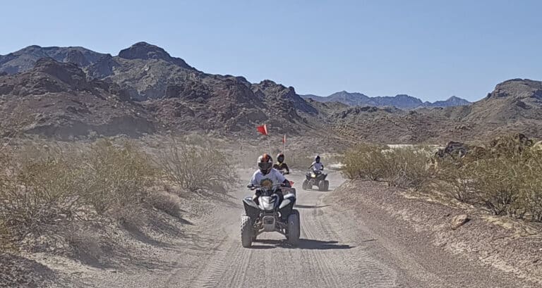 Experience thrilling ATV tours near Las Vegas, NV—ride dusty desert trails with red flags amid rocky hills and stunning Nevada views.