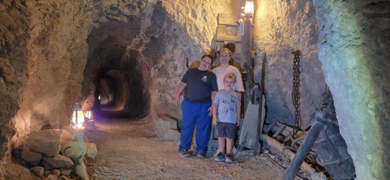 Family smiles inside a Nevada mining tunnel near Las Vegas, surrounded by lanterns—perfect for ATV tours or Ghost Town sightseeing!.