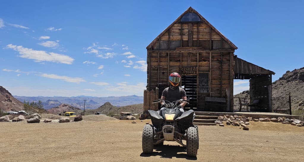 Helmeted rider on an ATV at a Nevada ghost town near Las Vegas, ready for RZR off-road tours by the Colorado River.