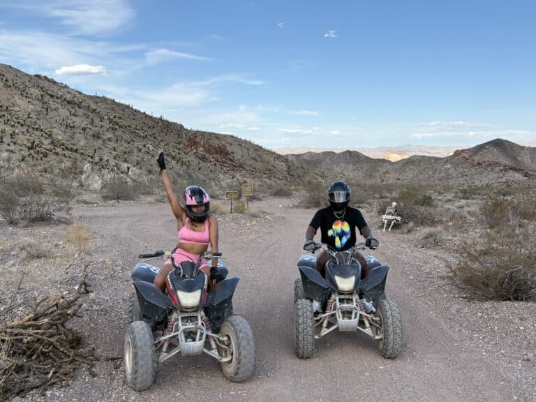 Riding ATVs near Las Vegas: two adventurers explore Nevadas desert trails, enjoying an exciting ATV tour by rocky hills.