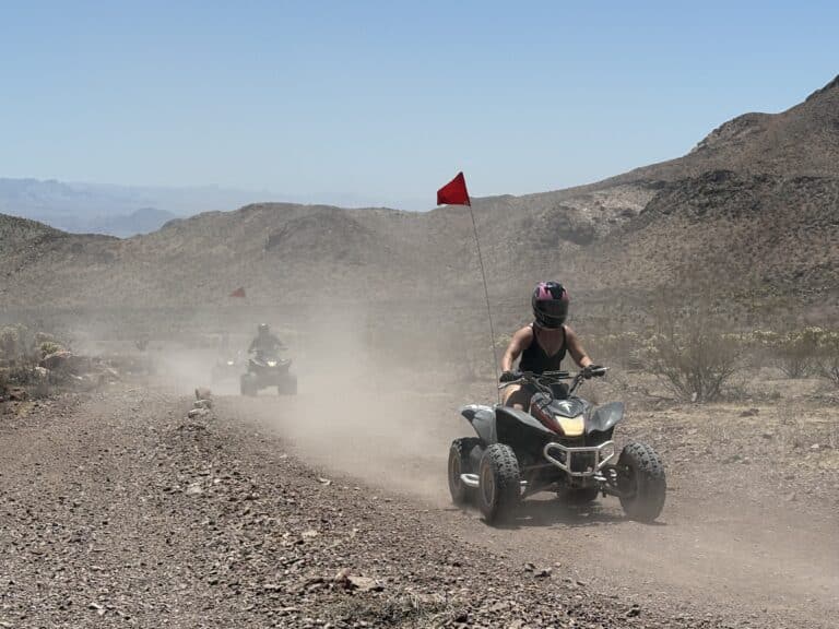 Experience thrilling Las Vegas ATV tours on dusty desert trails near the Colorado River, with red flags and scenic Nevada mountains.