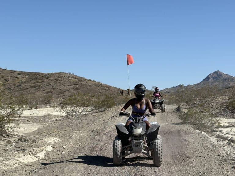 Experience thrilling ATV tours near Las Vegas, Nevada—ride desert trails with red flags past hills and bushes under a blue sky.
