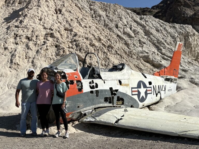 Three friends smile by an old Navy plane wreck on Nevada cliffs near the Colorado River—perfect for Las Vegas ATV or RZR tours!.
