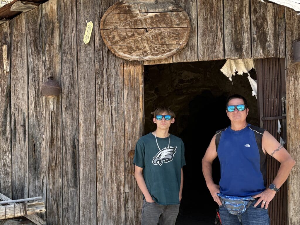 Two people in sunglasses pose at a rustic Nevada ghost town near the Colorado River—perfect for Las Vegas ATV and RZR tours!.