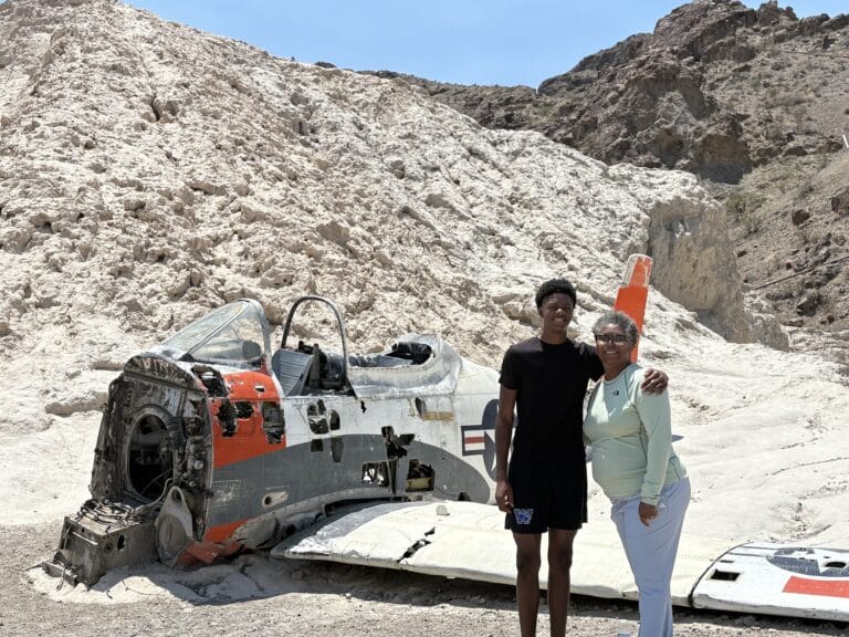 Smiling duo at a Nevada airplane wreck near Las Vegas—perfect for Ghost Town sightseeing & ATV tours by the Colorado River.