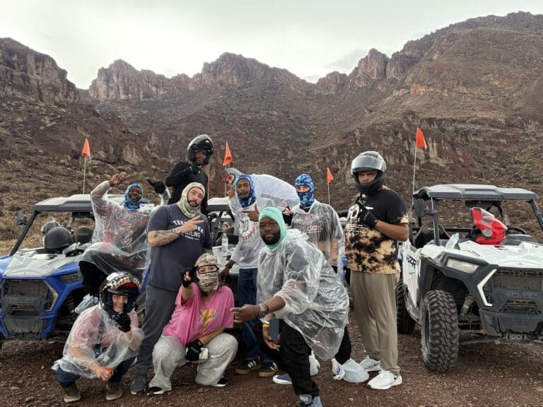 Adventurers in helmets and ponchos pose by RZR off-road vehicles amid Nevada’s rugged desert near Las Vegas & the Colorado River.