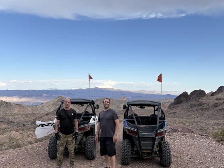 Two men with off-road vehicles on a rocky Nevada hilltop near Las Vegas, perfect for RZR ATV tours and Colorado River views.