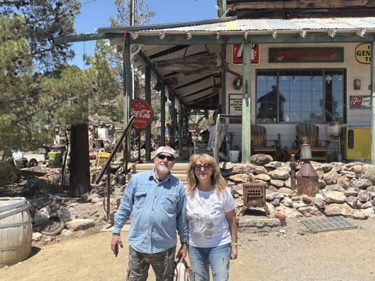 Smiling couple at a Nevada ghost town near the Colorado River, posing by a rustic general store before an ATV tour from Las Vegas.
