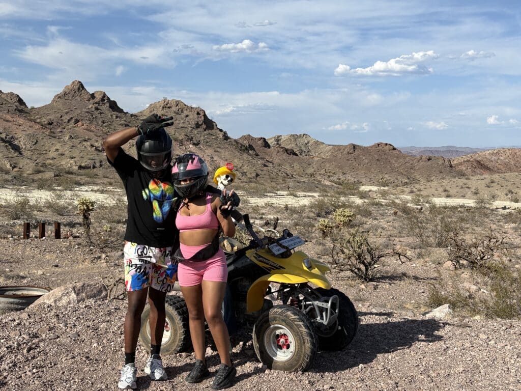 Two adventurers in colorful gear pose by a yellow ATV near Las Vegas, Nevada, ready for an ATV tour of the desert and Colorado River.