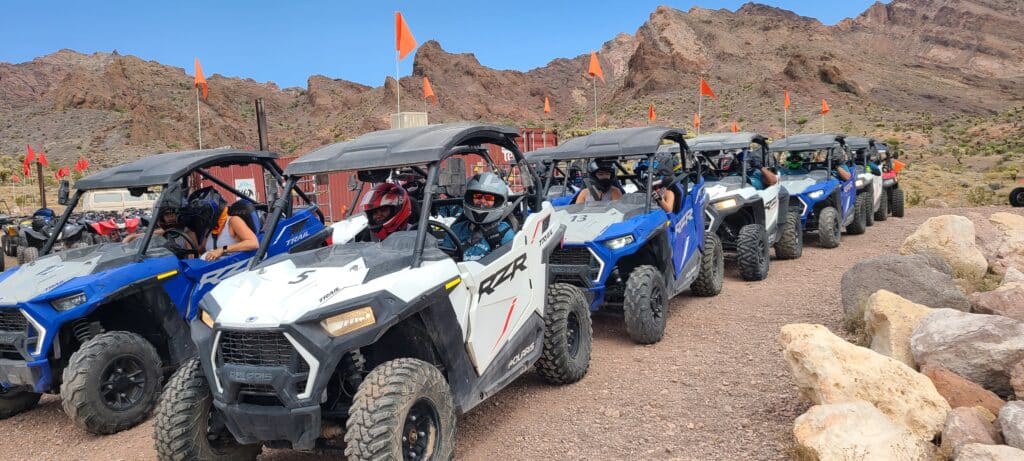 Get ready for Las Vegas ATV tours—drivers in helmets line up for RZR off-road rides near Nevadas rocky hills and Colorado River.