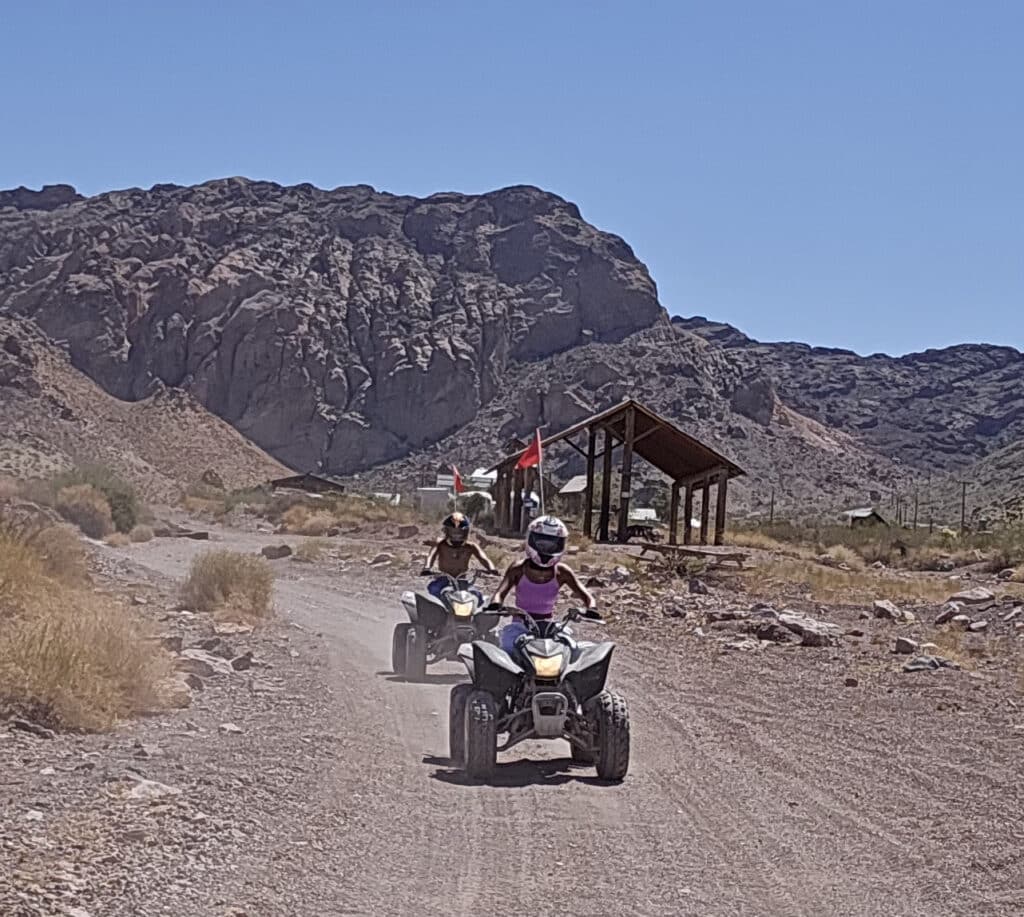Adventure seekers enjoy an ATV tour near Las Vegas, riding dusty trails by the Colorado River with Nevada mountains in view.
