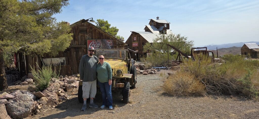 Couple poses by vintage yellow jeep in a Nevada ghost town near Las Vegas, perfect for sightseeing or RZR off-road adventures.