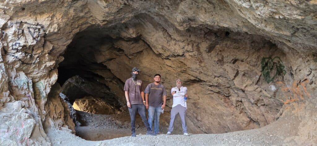Three explore a spacious, graffiti-marked Nevada cave near the Colorado River on a thrilling Las Vegas ATV adventure.