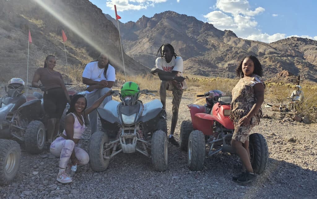 Five friends enjoy a Las Vegas ATV tour on rocky Nevada terrain, with mountains, RZR rides, and the Colorado River in view.