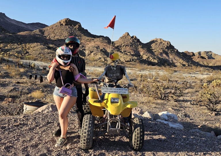 Riders in helmets pose by a yellow ATV near Las Vegas, Nevada, ready for an epic desert RZR tour along the Colorado River.