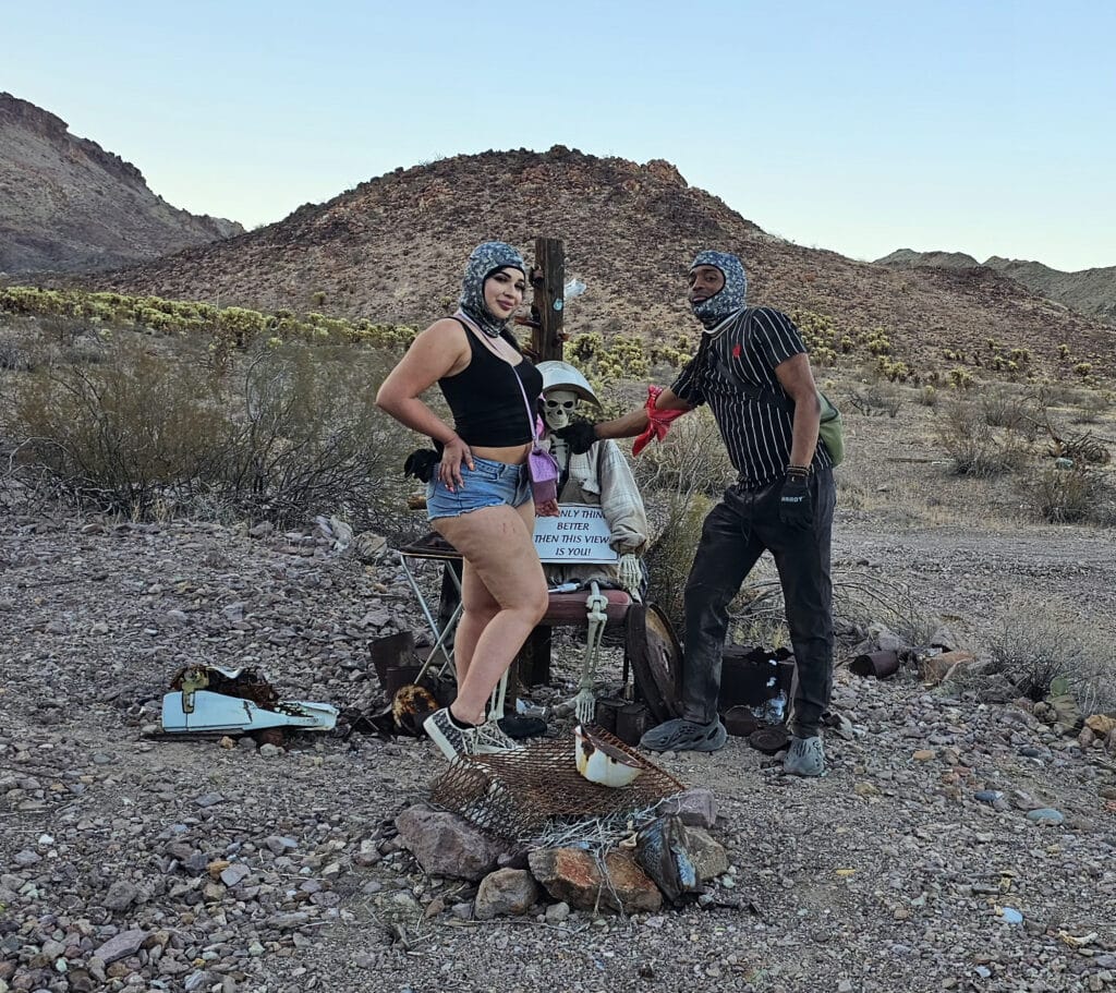Two helmeted friends pose with a skeleton display near Las Vegas on a Nevada desert ATV tour by the Colorado River.