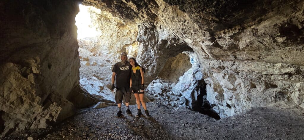Two adventurers explore a rocky Nevada cave near the Colorado River, sunlight streaming in—perfect for Las Vegas ATV or RZR tours.