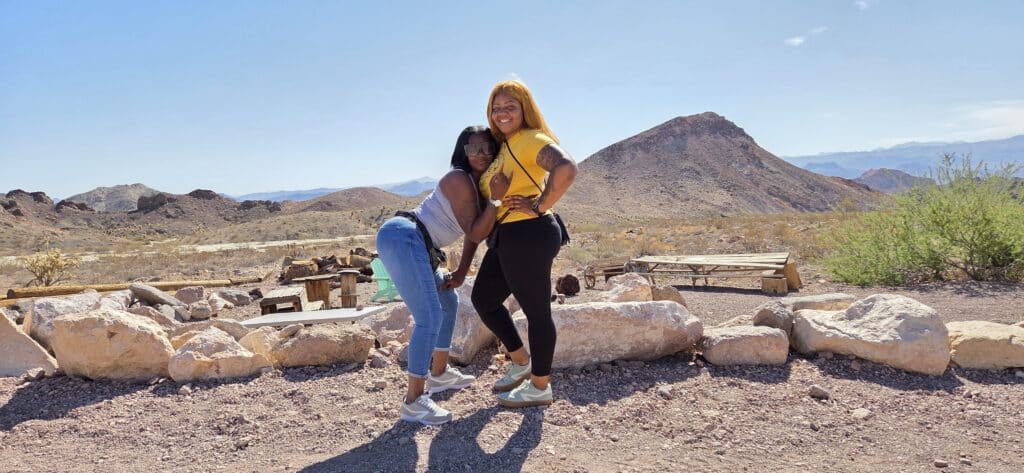 Two women pose playfully in Nevada’s desert near Las Vegas, with mountains and the Colorado River—perfect for ATV tours and off-roading.