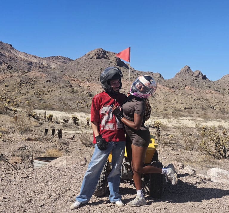 Two riders in helmets stand by a yellow ATV on a Nevada desert trail near Las Vegas, ready for an exciting ATV tour adventure.