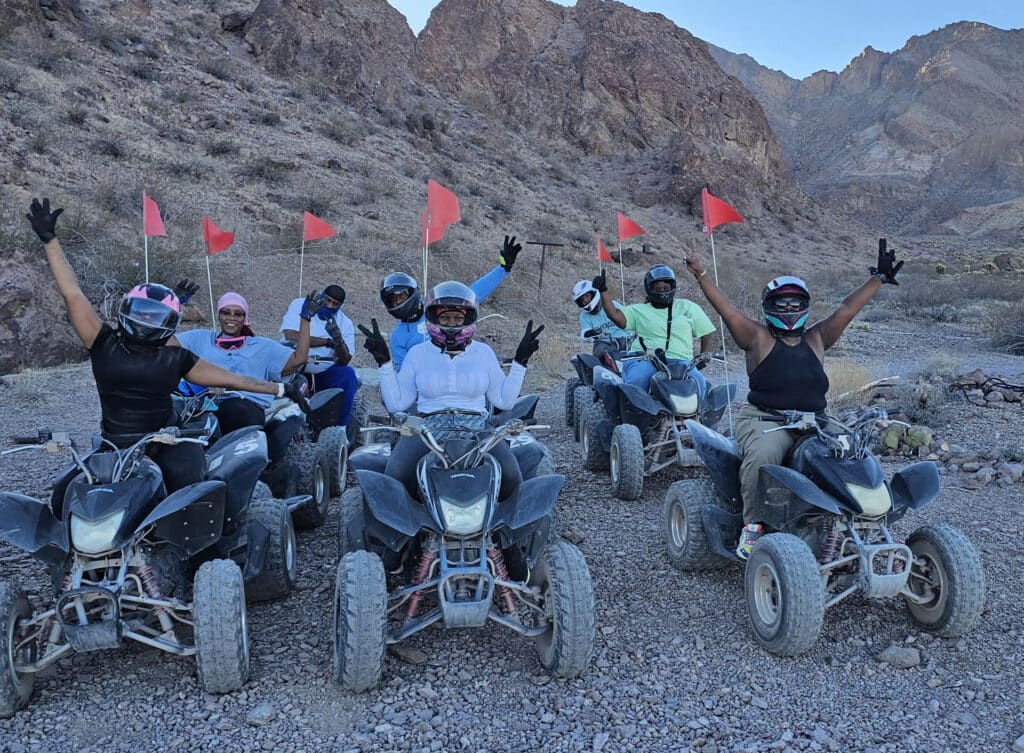 Adventurers on ATVs with red flags pose in Nevada’s rocky desert near Las Vegas during an epic ATV tour along the Colorado River.