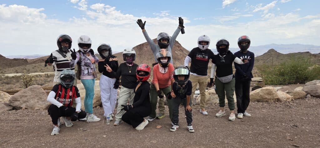 Group enjoying an ATV tour near Las Vegas, Nevada—posing on rocky terrain by the Colorado River with mountains in the background.