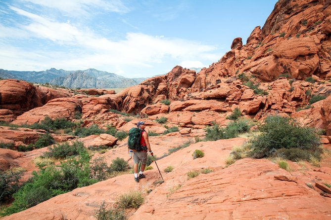 Hiker with backpack and trekking poles explores Nevada’s red sandstone near Las Vegas, Colorado River, and Ghost Town sights.