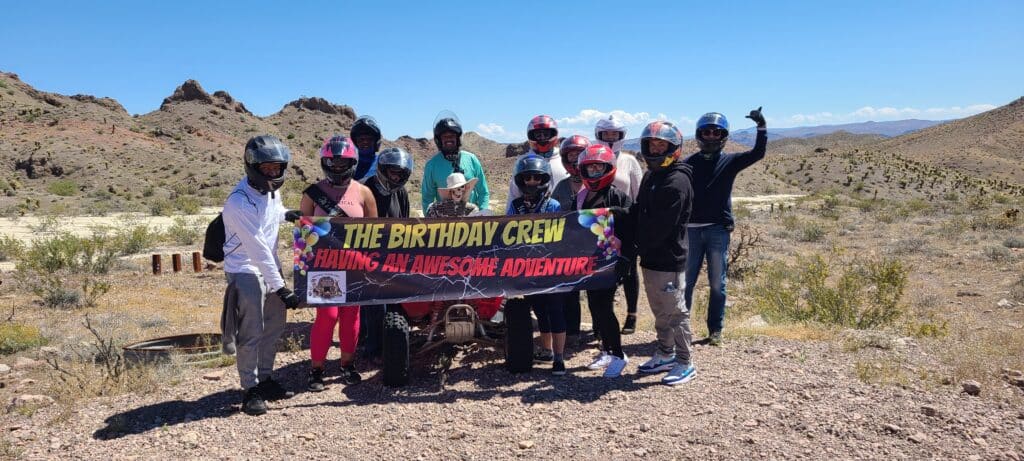 Smiling riders with helmets pose in Nevada’s desert on a Las Vegas ATV tour near the Colorado River—The Birthday Crew’s adventure!.