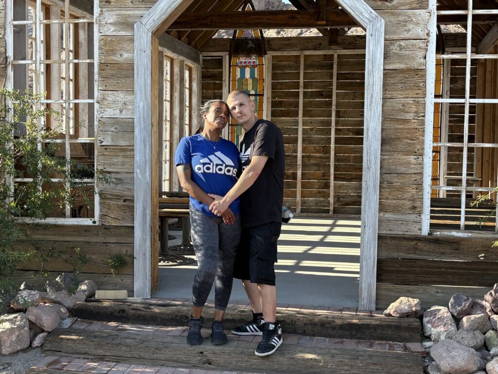 A happy couple embraces by a rustic wooden structure near the Colorado River, Las Vegas—perfect for ATV tours and ghost town sightseeing.