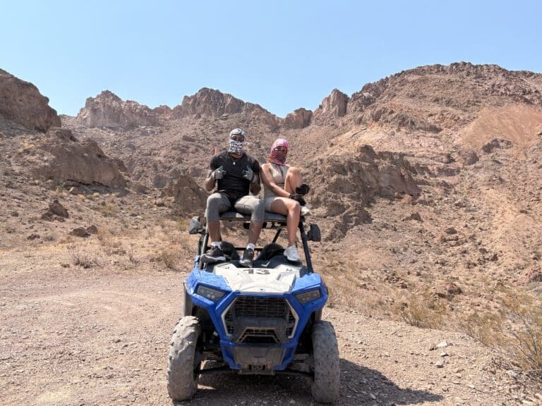 Adventurers in bandanas and sunglasses enjoy an ATV tour near Las Vegas, NV, on a desert trail by rugged Nevada mountains.
