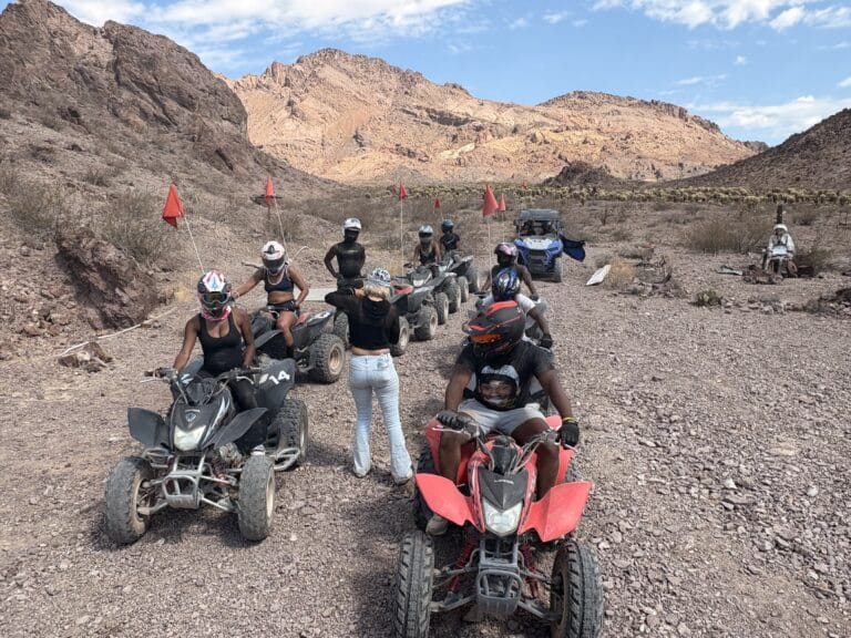 Adventurers in helmets line up on ATVs for a thrilling Nevada desert tour near Las Vegas, with red flags marking the rocky trail.