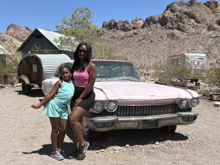 Smiling woman and girl by vintage pink car in Nevada desert near Las Vegas—perfect for ghost town sightseeing & RZR rides!.