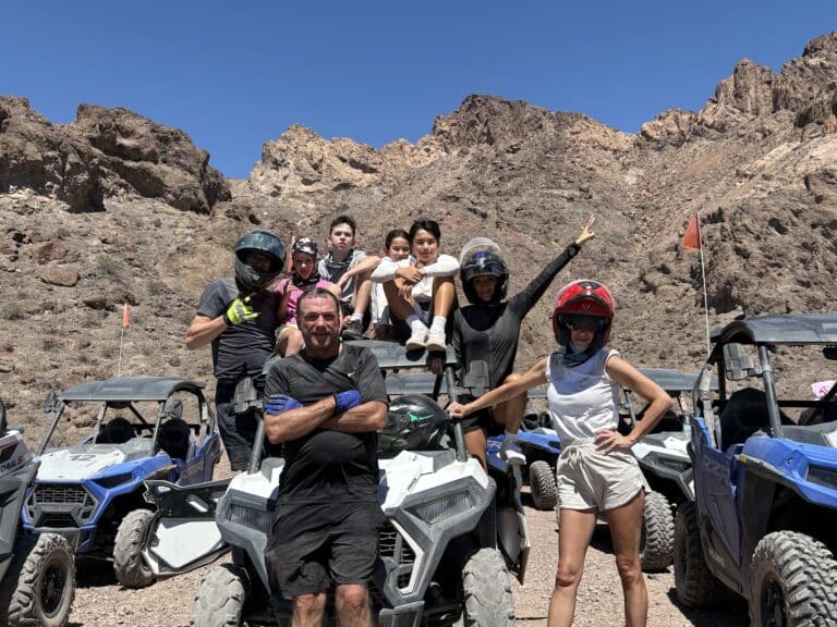Adventurers in helmets enjoy an ATV tour near Las Vegas, posing with RZR vehicles in Nevada’s stunning desert landscape.
