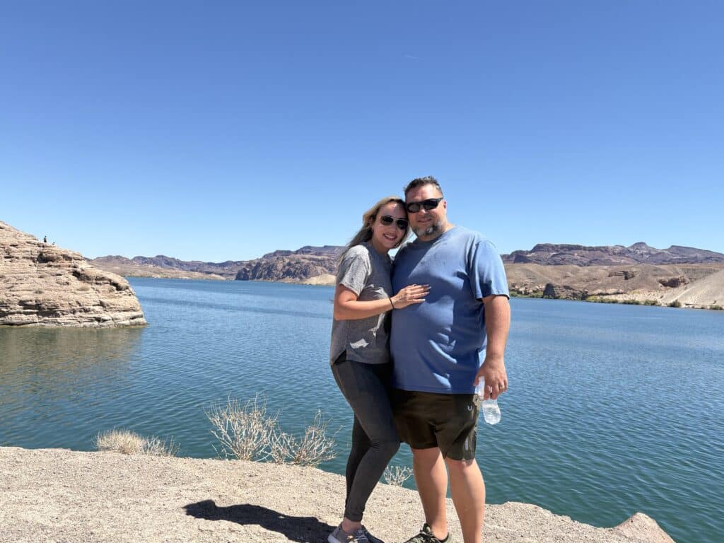 Smiling couple by the bright blue Colorado River near Las Vegas, Nevada—hugging after a thrilling ATV tour and Ghost Town sightseeing.