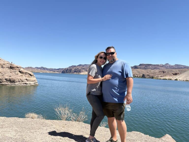 Smiling couple by the bright blue Colorado River near Las Vegas, Nevada—hugging after a thrilling ATV tour and Ghost Town sightseeing.