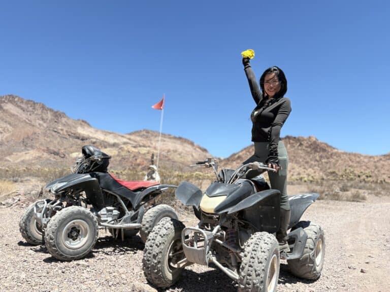 Smiling woman stands atop ATV in Nevada desert near Las Vegas, enjoying thrilling RZR off-road tour by the Colorado River.