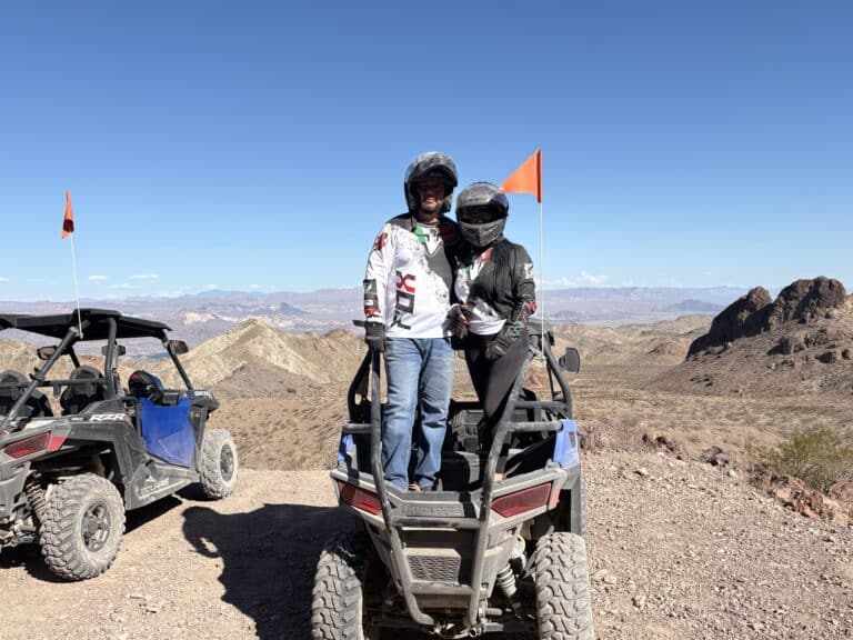 Adventurers in helmets enjoy an ATV tour near Las Vegas, Nevada, overlooking rocky desert and mountains by the Colorado River.