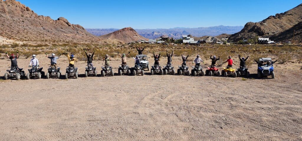 Adventurers on ATVs raise their arms amid Nevadas desert near Las Vegas, enjoying guided ATV tours by the Colorado River.