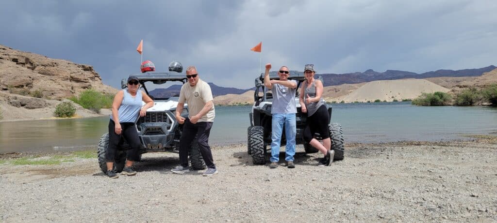 Adventurers pose by their ATVs on a Las Vegas lake near the Colorado River—perfect for Nevada RZR tours and off-road fun!.