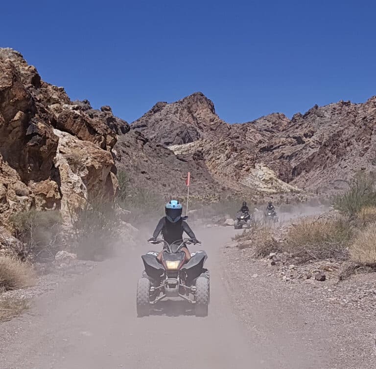 Experience thrilling ATV tours near Las Vegas: three riders explore Nevadas rocky desert trails under clear blue skies.