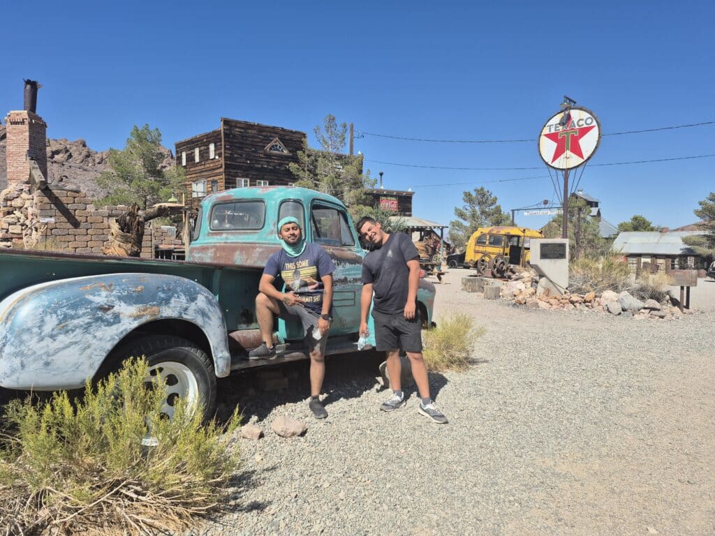 Two men pose by a vintage turquoise truck in a Nevada ghost town—ideal for Las Vegas ATV tours and Colorado River RZR adventures.