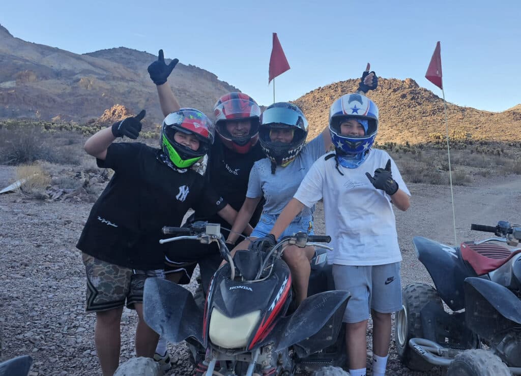 Four riders in helmets on ATVs enjoy an off-road adventure near the Colorado River in Nevada’s desert, close to Las Vegas.